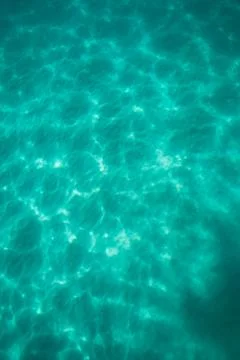 Light dancing on the sand below a tropical turquoise blue ocean Stock Photos