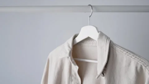 Light denim jacket hanging on white wooden hanger presents minimalist clothing Stock Footage 340266545
