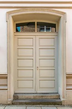 Light double doors under soft arch. Calm classic entrance. Stockfoto's