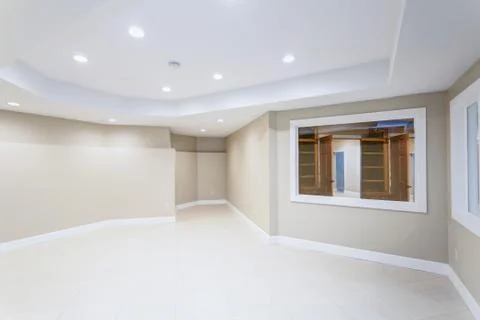 Light Empty basement room with beige tiled floor and white ceiling. Stock Photos
