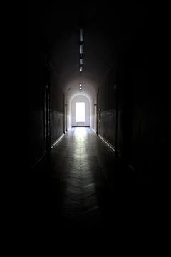 Light at the end of a long dark hallway invites exploration and curiosity in an Stock Photos