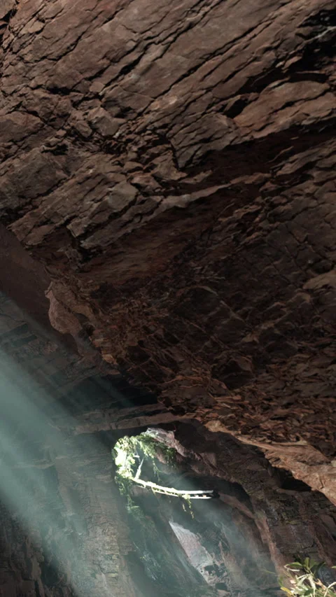 Light enters cave through opening in rocky ceiling during daytime exploration Stock Footage 339421936
