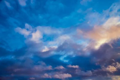 Light falls on the clouds in the evening sky, different shades of light in th Stock Photos