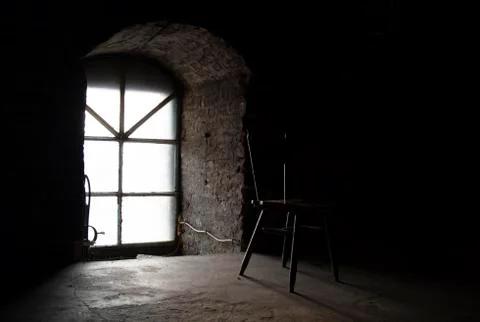 Light falls through the window on a chair in a dark room Stock Photos