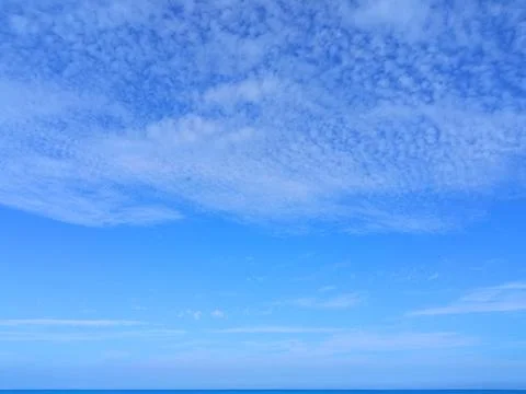Light feather clouds in the blue sky above the sea horizon Foto stock