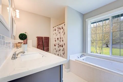 Light filled bathroom interior accented with double sink blue vanity cabinet  Stock Photos
