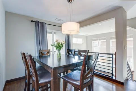 Light filled dining room with dark wood table set and blue curtains. Stock Photos