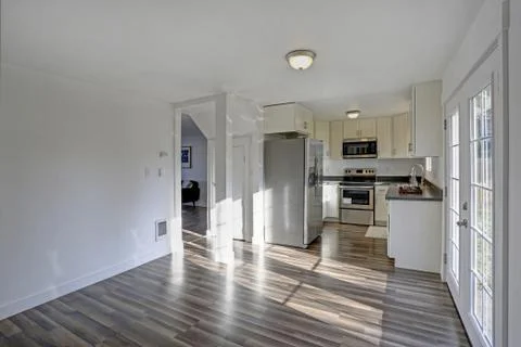 Light filled home interior features small compact kitchen with white cabinets Foto stock