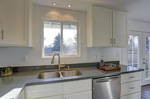 Light filled home interior features small compact kitchen with white cabinets Stock Photos