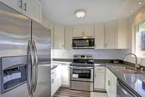 Light filled home interior features small compact kitchen with white cabinets Foto stock
