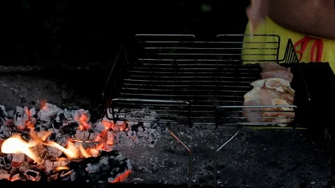In the light of the fire male hands put raw meat on the grill Stock Footage 114292554