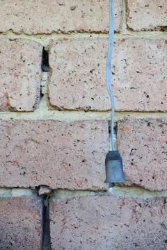 Light fixture connected to wire on brick wall in a building during daytime Foto stock