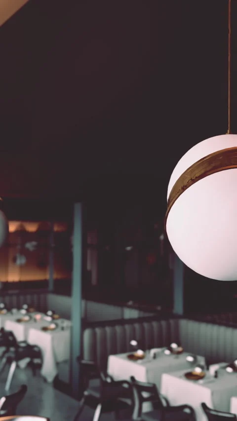 Light fixture hangs over empty tables in restaurant during evening hours Stock Footage 338383267
