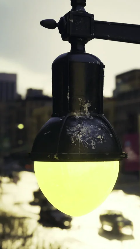 Light fixture hangs over water during dusk near city buildings Stock Footage 331677396