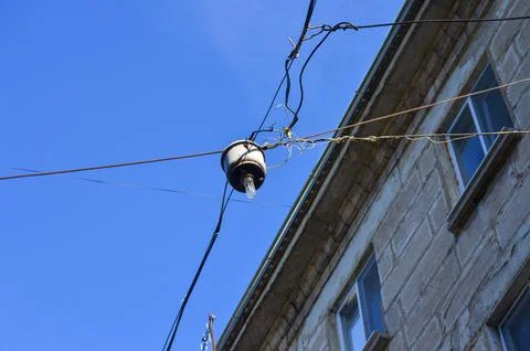 A light fixture, which appears to be a bulb, is hanging from a power line.  Stock Photos