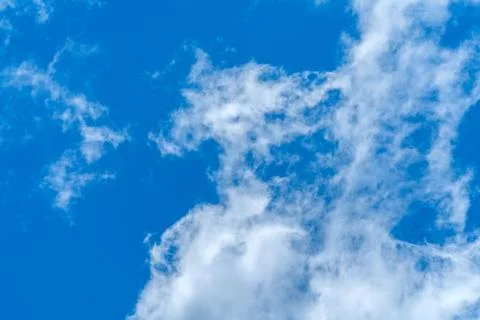 Light fluffy clouds against a bright blue sky background. Stock Photos