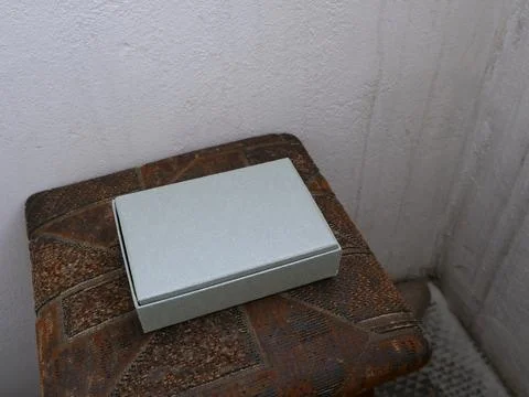 Light gift box lying on soft surface near wall in interior. Stock Photos