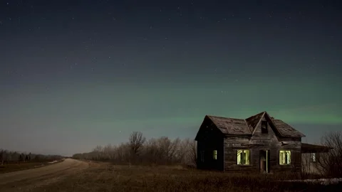 Light glows through the broken windows in a dilapidated spooky farmhouse.  Vídeo Stock 151114691