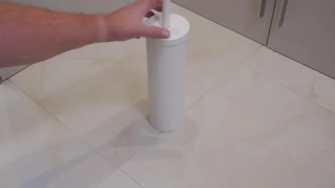 Light Grate: Hand Slides White Plastic Toilet Brush Holder on Tiled Floor. Vídeos de archivo 320808631