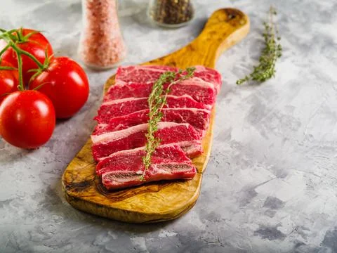 On a light gray background, meat steaks with a sprig of rosemary on a cutting Stock Photos