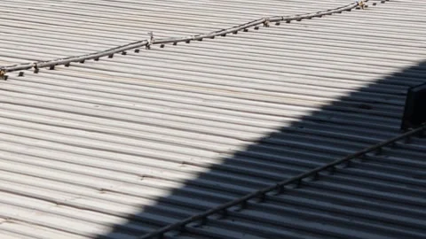 Light Gray Corrugated Metal Rooftop with Pipes and Diagonal Shadow in Daylight Stock Footage 339102212