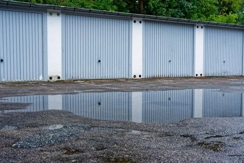 Light gray doors repeat, water gathers in a cracked lane Stock Photos