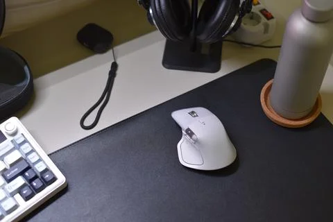 Light gray Logitech MX Master 4 wireless mouse on black desk mat Stock Photos
