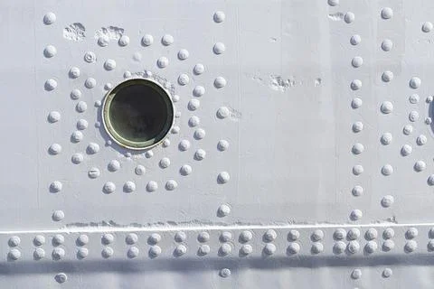 A light gray metal surface is covered with numerous round rivets. Stock Photos