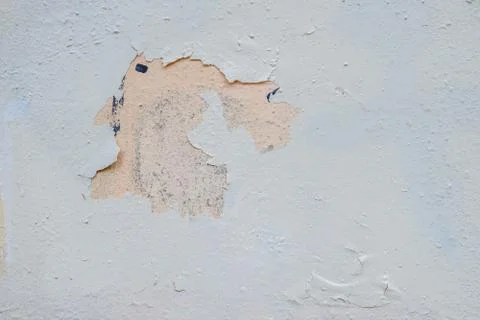 Light gray paint peels off the surface of an old metal sheet. Stock Photos
