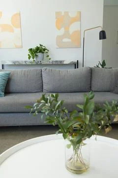 Light-gray sofa sitting in lounge under abstract art, coffee table holding vase Stock Photos