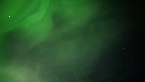 Light green Aurora Norther lights dance across the stary sky as a few white Stock Footage 339733383