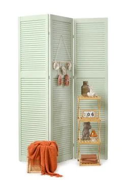 Light green folding screen with decorative elements, a wicker basket, and a w Stock Photos