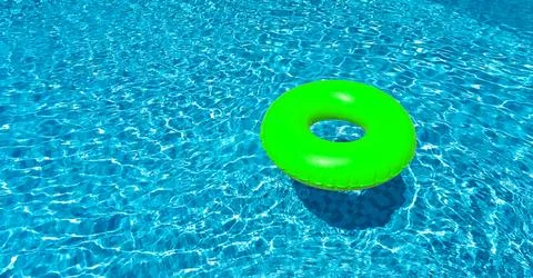 Light green ring floating in blue swimming pool. Inflatable ring, rest concept Foto stock