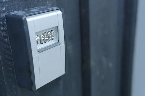 Light grey key safe wall safe with combination lock is attached to a dark w.. Stock Photos