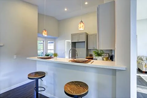 Light grey kitchen room interior with bar style kitchen island and round stoo Stock Photos