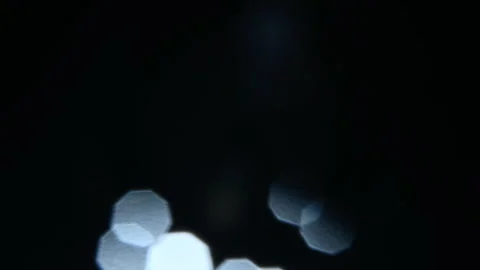The light hits the lens and creates beautiful highlights and bokeh on a dark Vídeo Stock 303642048