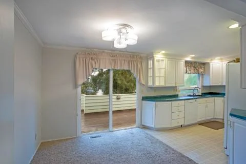 Light home interior with white kitchen cabinetry and dining area with exit to Stock Photos