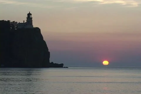 Light house on cliff with low gold sunball at sea horizon Video stock 192545157