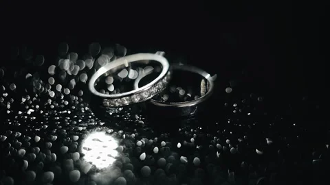 The light illuminates two silver rings lying on a dark surface Stock Footage 266554524