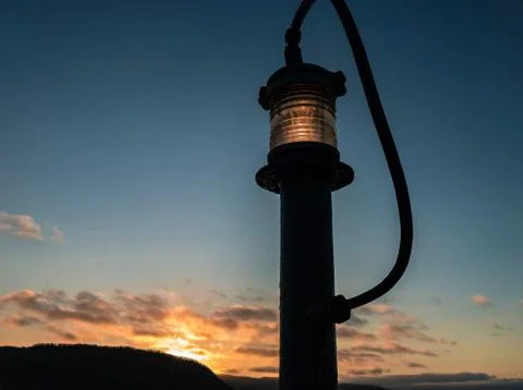 Light from a lamp post from the rear deck of a ship against the sunset in the 写真素材