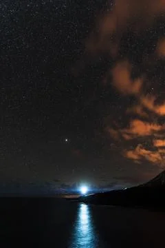 Light of the lighthouse pointing to the camera under the stars Stock Photos