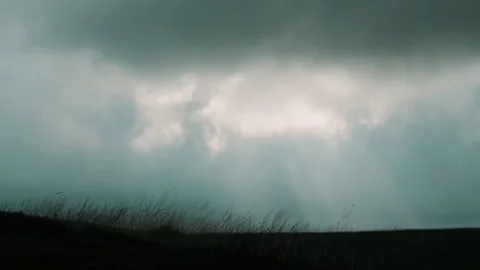 Light making way through moving clouds behind silhouette field Stock Footage 130261797