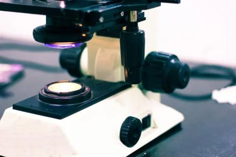 A light microscope with knobs and screws with light on Stock Photos