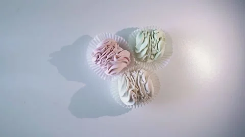 The light moves around the three marshmallows, which casts a shadow on a white Stock Footage 221017699
