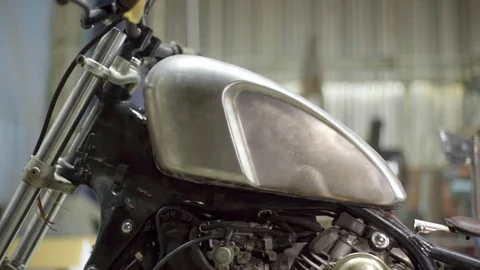 Light moves over unpainted metal fuel tank of custom bike Stock Footage