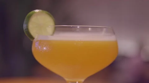 Light orange cocktail with a slice of lime on the rim. A refreshing fruit Vidéo 256076088