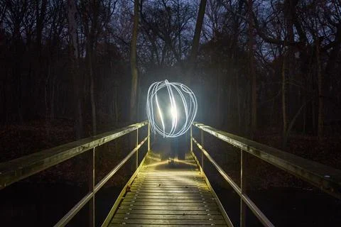 Light Painted Orb on Illuminated Forest Footbridge at Night Fotos de archivo