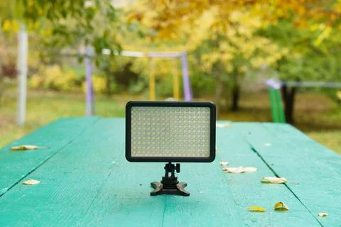 Light panel on a green table in an autumn garden with colorful leaves Stock Photos