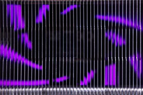 Light patterns shine through metal wires in a close-up view of a modern art Stock Photos