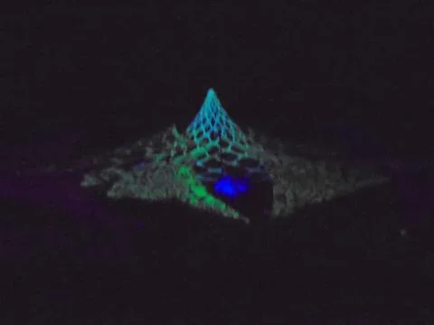 Light performance art: fluorescent blue-green web rotating in conical shape. Stock Photos